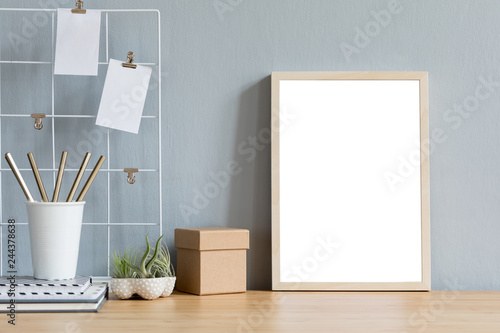Home interior with mock up photo frame on the brown wooden table with office accesories, paper box, tillandsia in design pots, notebook and notes. Grey walls. Minimal concept of mockup. © FollowTheFlow