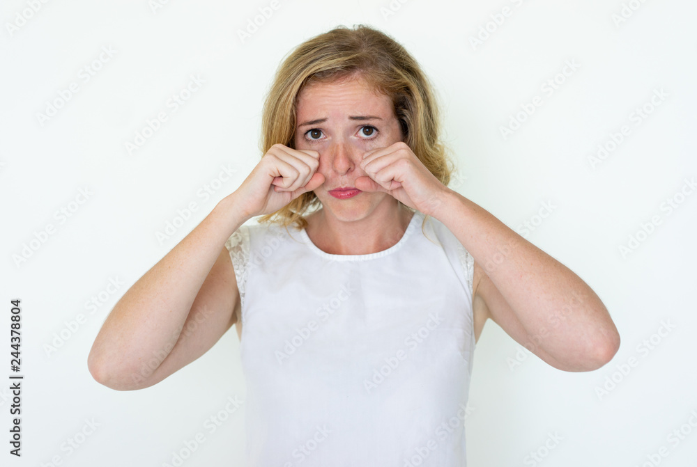 Sad young pretty woman pretending to cry. Lady looking at camera and wiping tears with fists. Sadness concept. Isolated front view on white background. Sad young pretty woman pretending to cry. Lady looking at camera and wiping tears with fists. Sadness concept. Isolated front view on white background.
