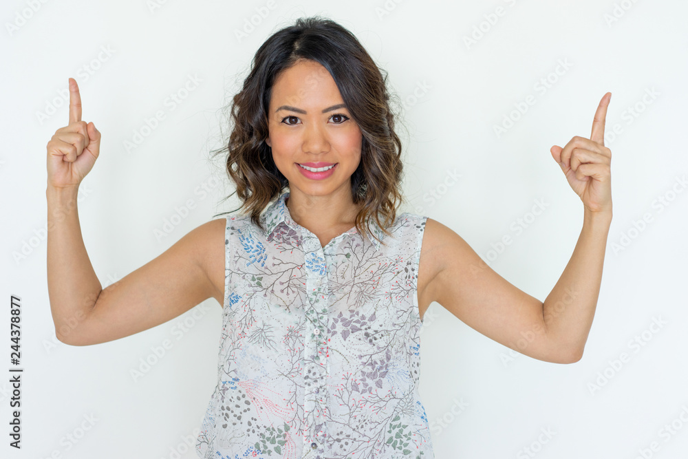 Smiling young woman pointing upwards with both forefingers. Pretty Asian lady recommending something. Advertisement concept. Isolated front view on white background. Smiling young woman pointing upwards with both forefingers. Pretty Asian lady recommending something. Advertisement concept. Isolated front view on white background.