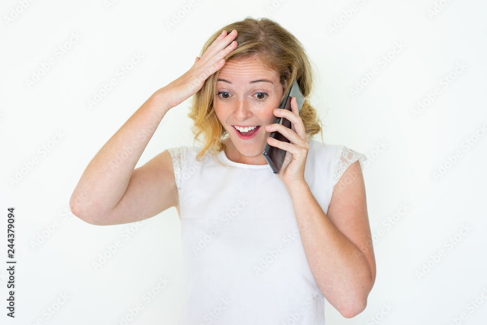 Surprised young pretty woman talking on smartphone. Excited lady touching head. Surprising news concept. Isolated front view on white background. Surprised young pretty woman talking on smartphone. Excited lady touching head. Surprising news concept. Isolated front view on white background.