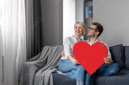 Smiling couple with heart relaxing on couch