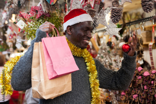 Smiling man in Santa hat selecting festive Christmas decoration