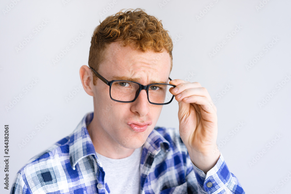 Serious young man frowning and adjusting glasses. Guy looking at camera. Smart man concept. Isolated front view on white background. Serious young man frowning and adjusting glasses. Guy looking at camera. Smart man concept. Isolated front view on white background.