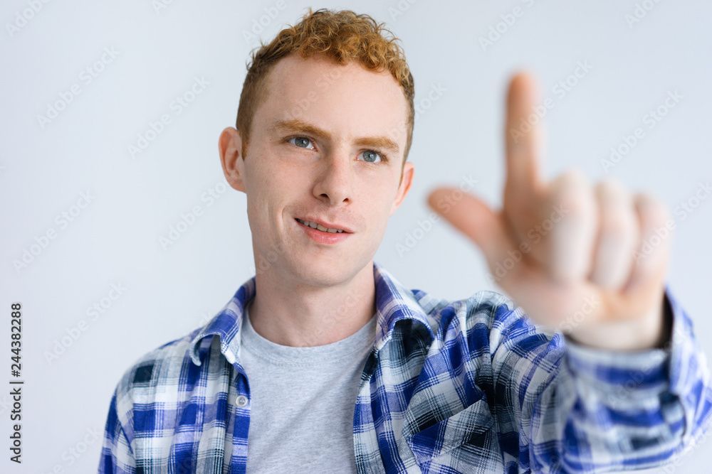 Smiling young guy touching invisible wall. Handsome business man standing and pointing at something. Promotion concept. Isolated front view on white background. Smiling young guy touching invisible wall. Handsome business man standing and pointing at something. Promotion concept. Isolated front view on white background.