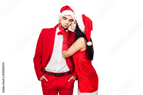 young couple having fun at a christmas theme party. young man and woman in red suits with Santa hats