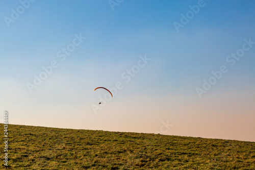 A paraglider against a clear winter sky, over Sussex countryside