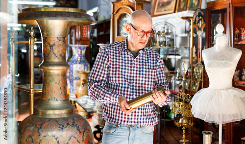 Portrait of mature man choosing vintage goods at antiques shop photo