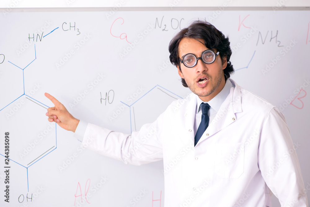 Young funny chemist in front of white board Young funny chemist in front of white board