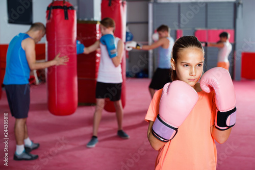 Girl in gloves posing during boxing training at gym © JackF