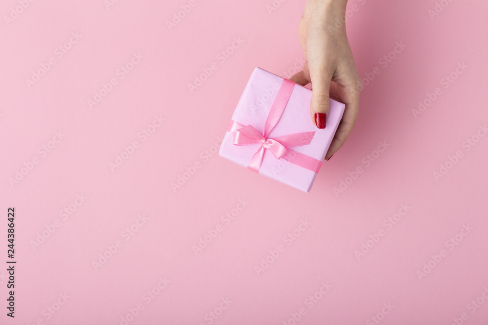 girl holding a present in hands, women's hands open the box wrapped in decorative paper on a pastel pink background, top view, concept holiday and gifts girl holding a present in hands, women's hands open the box wrapped in decorative paper on a pastel pink background, top view, concept holiday and gifts
