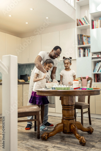 Father and daughters cooking in the morning in spacious kitchen