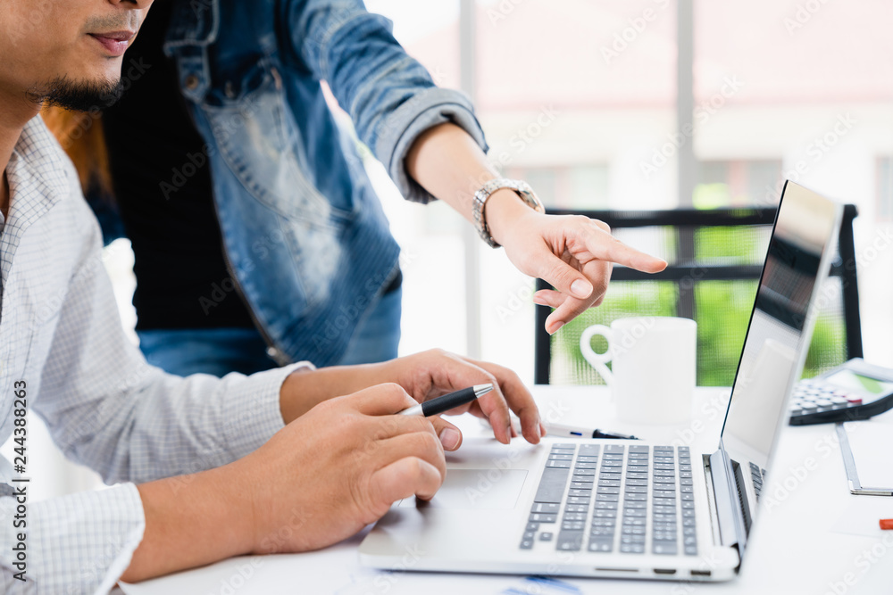 Casual businessman and team working discussing about business on laptop in modern home office. Woman hand pointing at computer screen show business data to team Casual businessman and team working discussing about business on laptop in modern home office. Woman hand pointing at computer screen show business data to team