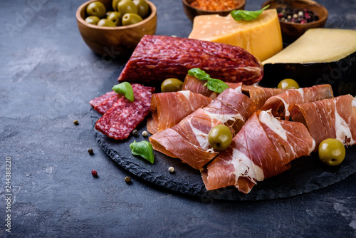 meat plate, prosciutto and cheese, salami, sausage and olives on gray background
