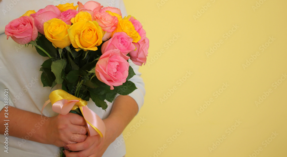 A girl in the blue dress holding bouquet of yellow and pink roses on a light-yellow background. Copyscape for your text.