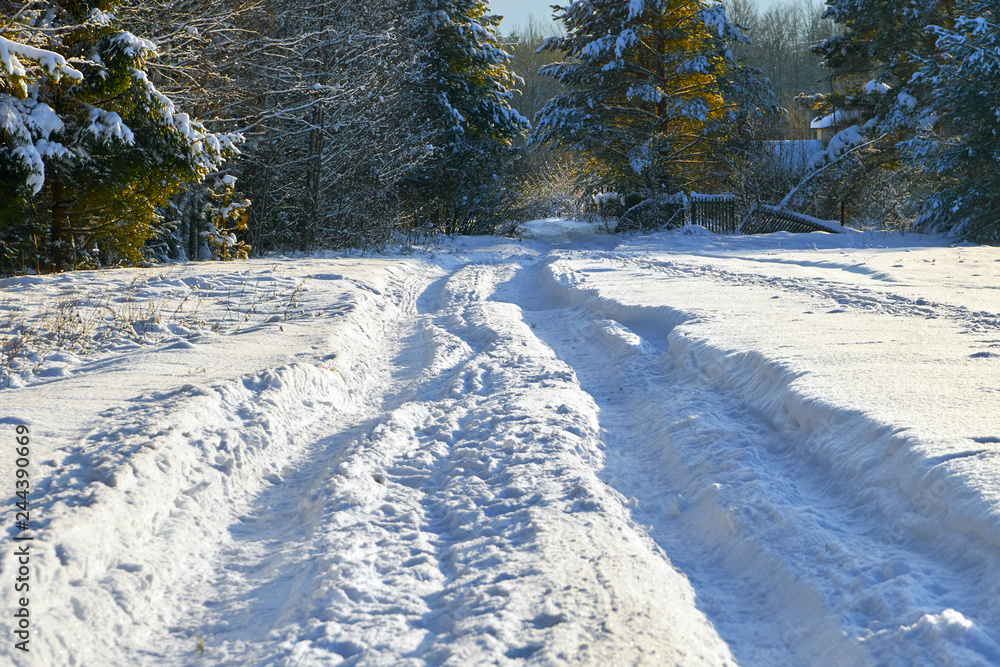 Winter landscape with a country road with very deep ruts in the snow