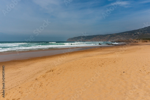 Vast golden sand beach on the Portuguese coast under a moody sky. Guincho Beach landscape in Cascais  Portugal a popular destination for surfers.