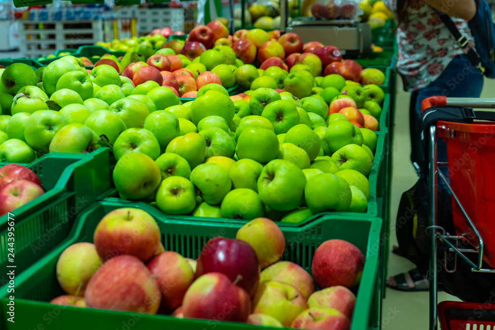 Bunch of green and red apples on boxes in supermarket.