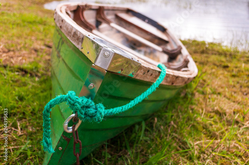 Bow closeup of a green fishing rowboat tied down on the green grass lake shore. Scene at Blessington Lake in Wicklow Mountains, Ireland. photo