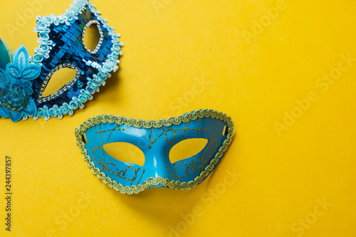 Table top view aerial image of beautiful colorful carnival season or photo booth prop Mardi Gras background.Flat lay object blue mask on modern yellow wallpaper.Free space for creative design mock