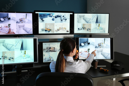 Security guard monitoring modern CCTV cameras in surveillance room