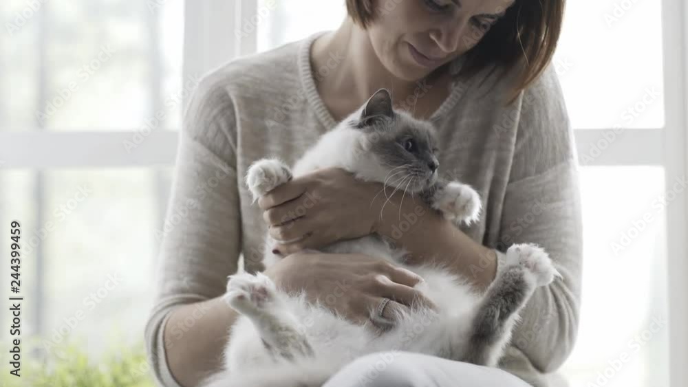 Woman holding and petting her cute cat next to a window Woman holding and petting her cute cat next to a window