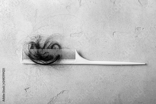 Comb with fallen down hair on grey background
