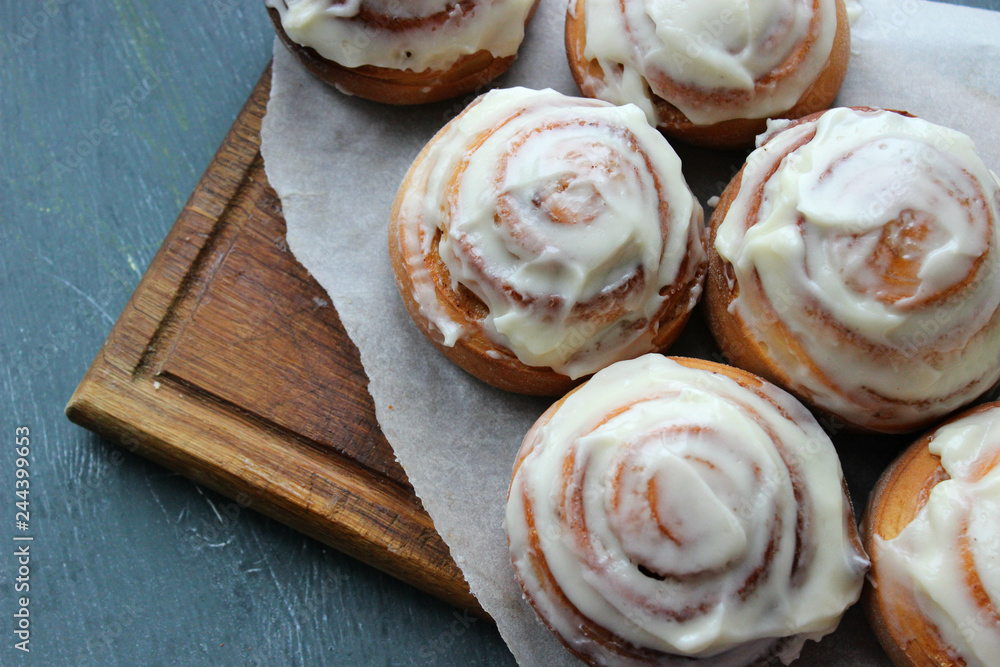 Beautiful fresh cinnamon rolls close-up on wooden grunge texture table. Fragrant homemade cakes, Cinnabon. A Cup of tea on a white saucer, cinnamon sticks. Delicious Breakfast buffet. Beautiful fresh cinnamon rolls close-up on wooden grunge texture table. Fragrant homemade cakes, Cinnabon. A Cup of tea on a white saucer, cinnamon sticks. Delicious Breakfast buffet.