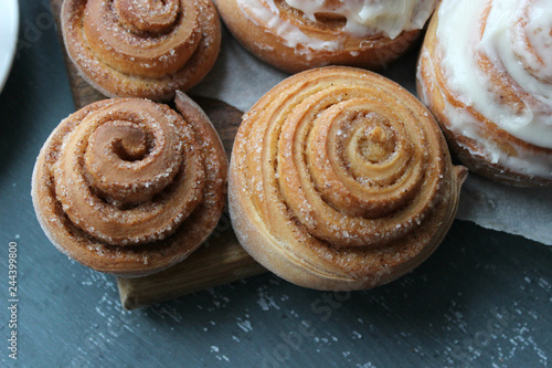 Beautiful fresh cinnamon rolls close-up on wooden grunge texture table. Fragrant homemade cakes, Cinnabon. A Cup of tea on a white saucer, cinnamon sticks. Delicious Breakfast buffet.
