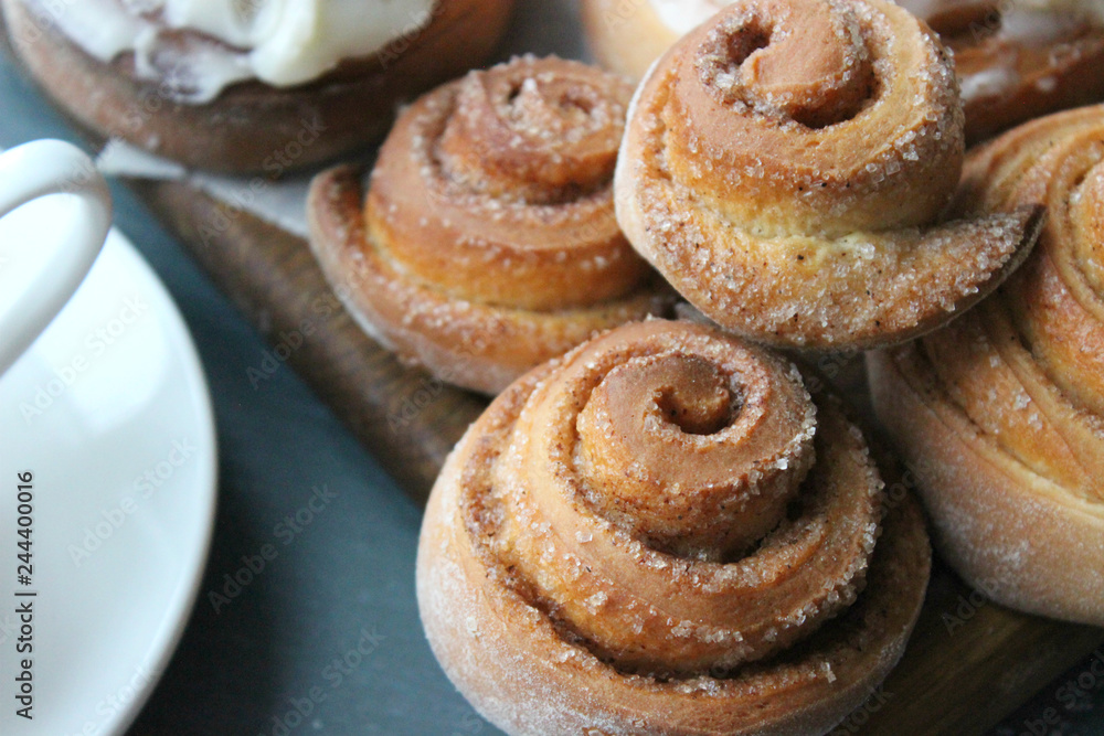 Beautiful fresh cinnamon rolls close-up on wooden grunge texture table. Fragrant homemade cakes, Cinnabon. A Cup of tea on a white saucer, cinnamon sticks. Delicious Breakfast buffet. Beautiful fresh cinnamon rolls close-up on wooden grunge texture table. Fragrant homemade cakes, Cinnabon. A Cup of tea on a white saucer, cinnamon sticks. Delicious Breakfast buffet.