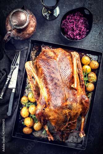 Traditional roasted stuffed Christmas duck with blue kraut and potatoes as top view on a board