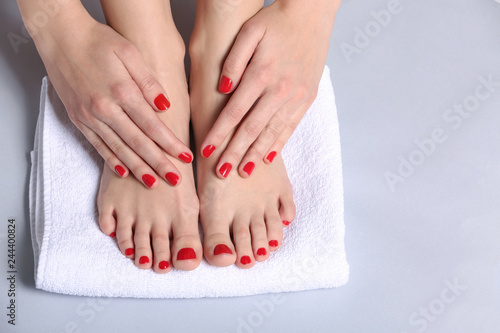 Young woman with beautiful pedicure and manicure on light background
