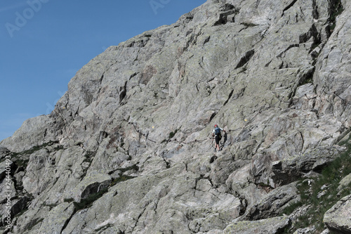 Woman walker climbing waymarked trail to alpine pass in summer