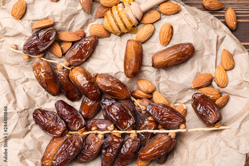 Sweet dried dates with almonds and honey dipper on table Sweet dried dates with almonds and honey dipper on table