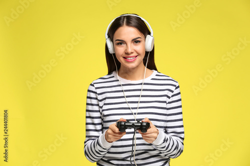 Beautiful happy woman playing computer game on color background