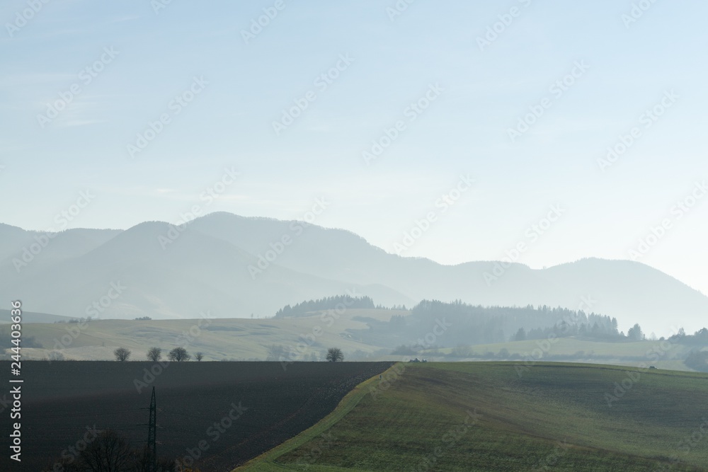Fototapeta premium Misty morning on meadow with trees and views. Slovakia