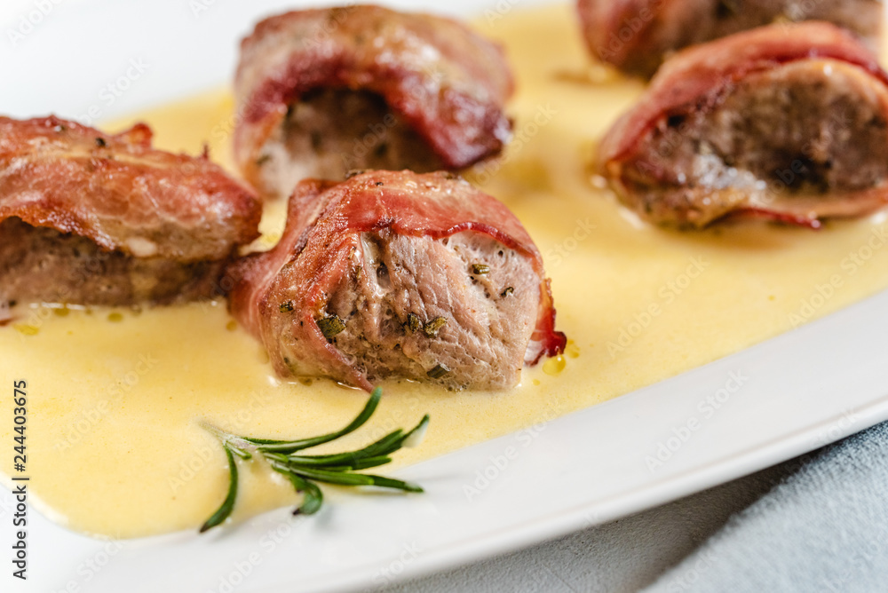Baked pork tenderloin wrapped in bacon and served in a cheese sauce with rosemary