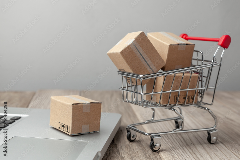 Delivery of the order from the online store. Online shopping. Boxes with goods in the shopping basket on the table with laptop Delivery of the order from the online store. Online shopping. Boxes with goods in the shopping basket on the table with laptop