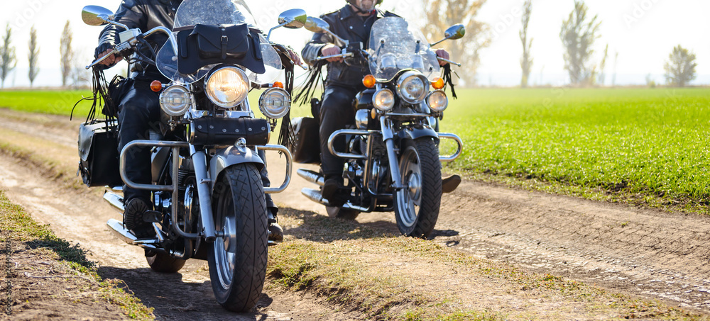 Obraz premium Two Motorcycle Drivers Riding Custom Chopper Bikes on an Autumn Dirt Road in the Green Field. Adventure Concept.