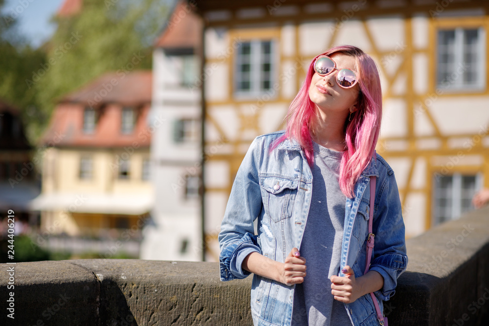 Outdoor portrait of a young beautiful confident woman posing on the street. Model wearing stylish sunglasses. Girl looking up. Female fashion.