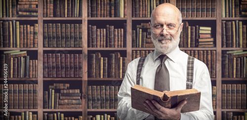 Academic professor in the library holding a book photo