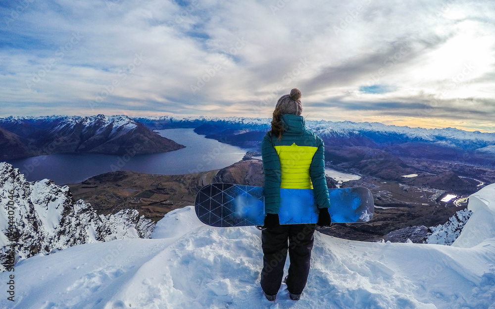Winter sport activity.Woman holding snowboard, overlooking mountain landscape freedom, enjoying a winter, cold season. Having fun on the snow, mountains, ski area, Remarkables, New Zealand, Queenstown