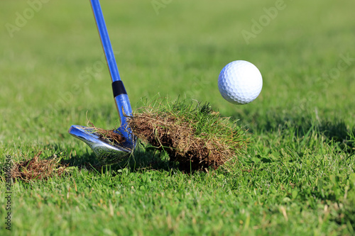 chipping golf ball out of the rough grass with a big divot photo