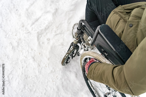 Disabled handicapped man has a hope. He sits in a wheelchair and looks at a mountain of snow. The complexity of the movement of the disabled. On a wheelchair in the winter.