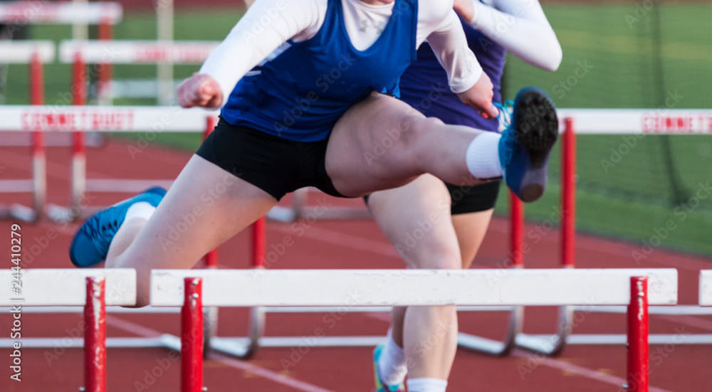 high school girls racing the hurdles outdoors
