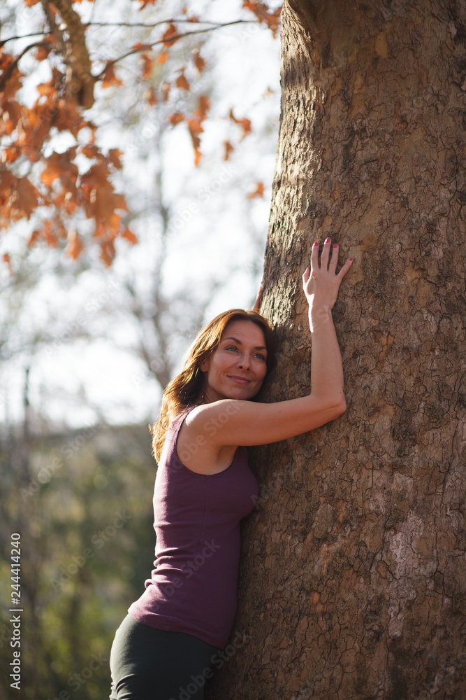 woman hugging a tree in the park after exercise woman hugging a tree in the park after exercise
