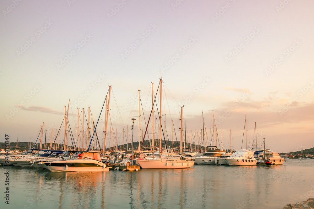 Beautiful view of the marina: yachts with masts against the background of the islands in the light of the setting sun. Adriatic coast, Croatia