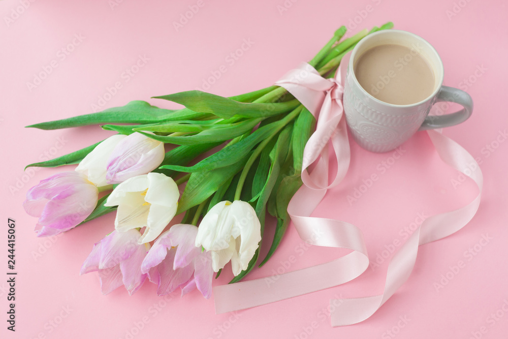 Bouquet of tulips and a coffee cup on a pink pastel background. Wonderful spring breakfast on Mother's Day or Women. Flat lay. View top. Selective focus.