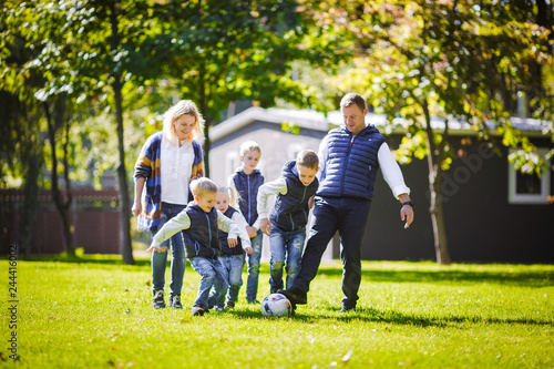 October 6, 2018 Ukraine. Kiev. theme family outdoor activities. big friendly Caucasian family six mom dad four children playing football, running ball on lawn, green grass lawn near house sunny day © Elizaveta