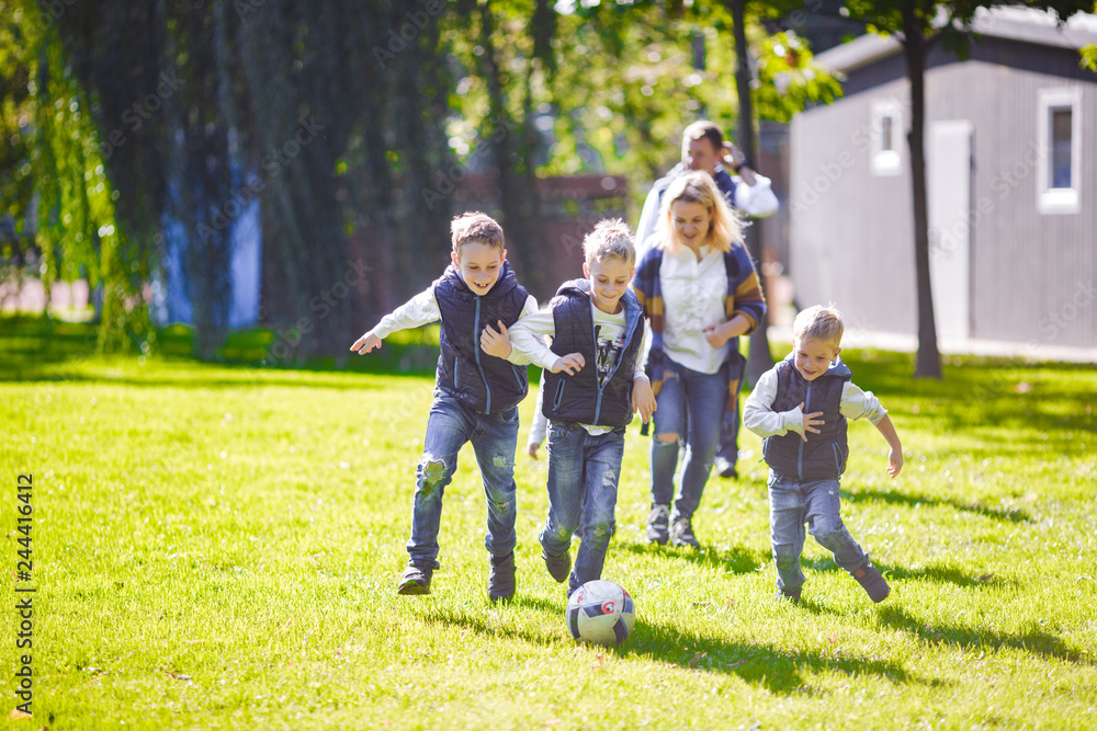 October 6, 2018 Ukraine. Kiev. theme family outdoor activities. big friendly Caucasian family six mom dad four children playing football, running ball on lawn, green grass lawn near house sunny day October 6, 2018 Ukraine. Kiev. theme family outdoor activities. big friendly Caucasian family six mom dad four children playing football, running ball on lawn, green grass lawn near house sunny day