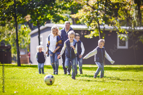 October 6, 2018 Ukraine. Kiev. theme family outdoor activities. big friendly Caucasian family six mom dad four children playing football, running ball on lawn, green grass lawn near house sunny day
